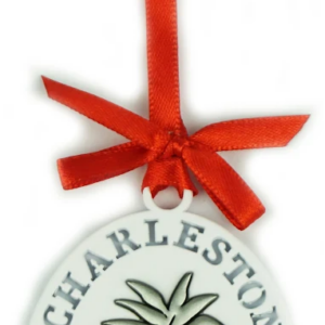 Ornament with a red ribbon tied around it, featuring a pineapple design and the words "Charleston